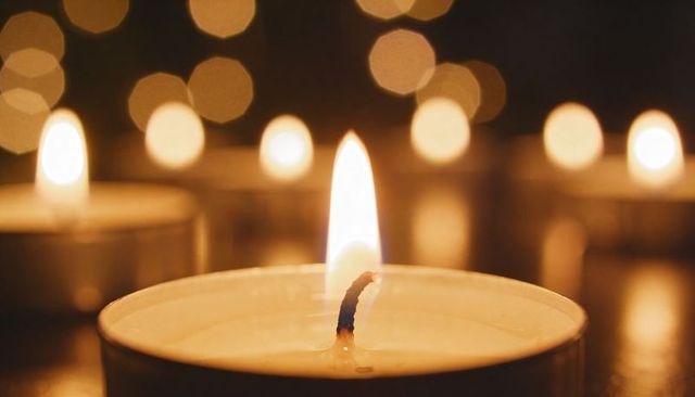 Tealight candle flame with melted wax and bokeh lights, intimate close-up for relaxation
