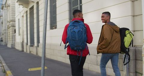 Friends chatting on urban street with backpacks