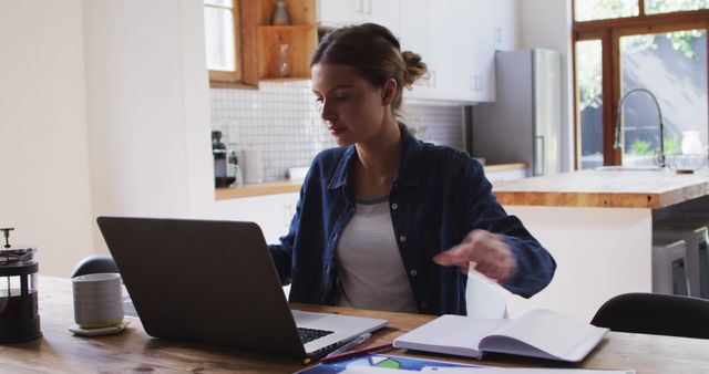 Young Woman Working on Laptop in Kitchen with Open Notebook - Download Free Stock Images Pikwizard.com