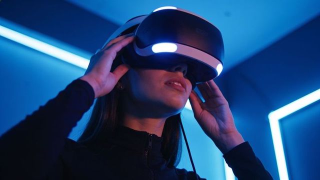Woman adjusting vr headset in neon-lit gaming booth, immersive futuristic virtual reality