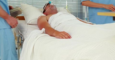 Male patient receiving oxygen and being monitored by medical staff on hospital stretcher