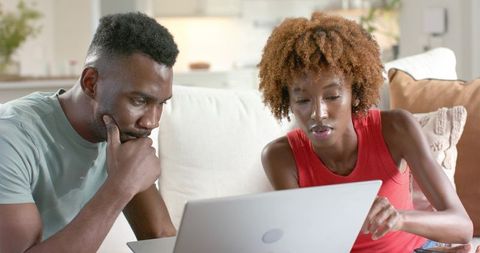 African american couple researching finances and planning budget on laptop in living room