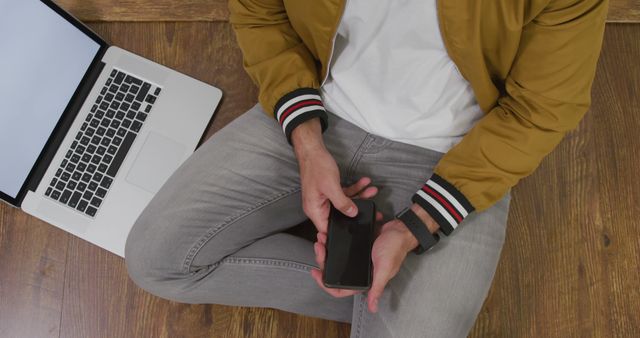 Man Using Smartphone While Sitting on Floor with Laptop - Download Free Stock Images Pikwizard.com