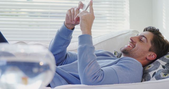 Smiling Man Relaxing on Couch and Using Smartphone at Home - Download Free Stock Images Pikwizard.com