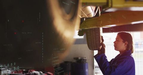 Female mechanic inspecting car tire on lift