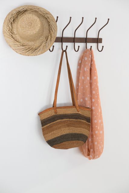 Hat, bag and scarf hanging on hook against white wall