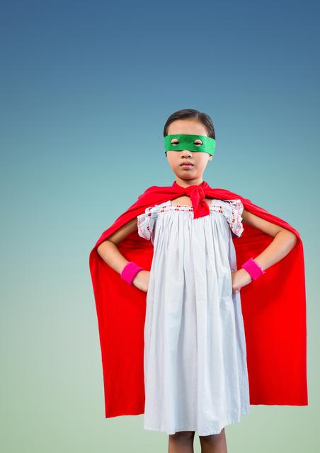 Portrait of a superhero kid in red cape and green eye mask 