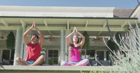Biracial Couple Meditating in Garden on a Sunny Day