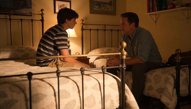 Father and teen son having heart-to-heart on twin beds night lamp-lit cozy family bonding moment