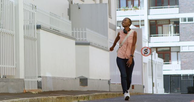 Joyful young woman walking on urban street with headphones - Download Free Stock Images Pikwizard.com