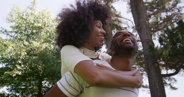 Happy couple enjoying nature with piggyback ride under trees - Download Free Stock Images Pikwizard.com