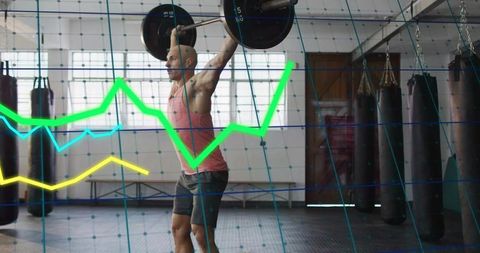 Mid-adult man lifting overhead barbell in gym with digital performance graphs overlay