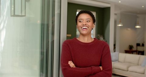 Smiling woman relaxing by modern glass door in cozy living room