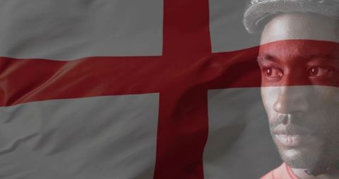 Gazing man wearing cap contemplating while st george's cross flag overlaying textured folds