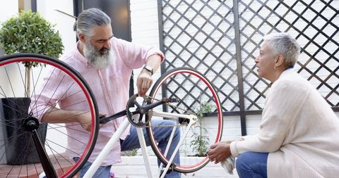 Couple maintaining bicycle together on sunny patio