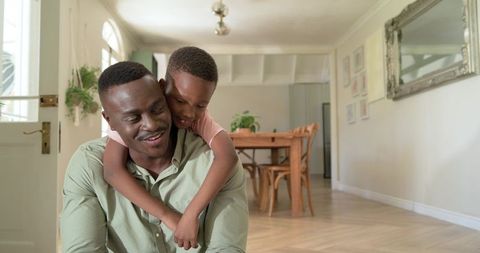 African american father and son sharing warm hug in sunlit modern home interior