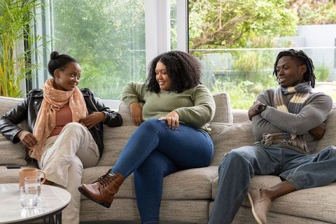 African american friends chatting on cozy sectional sofa, relaxed living room gathering