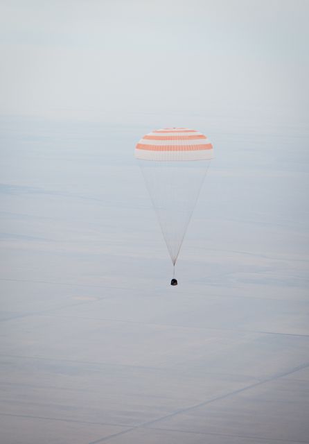 The image captures the Soyuz TMA-19 spacecraft descending with a parachute over Arkalyk, Kazakhstan on November 26, 2010. This event occurs as the Expedition 25 crew returns from nearly six months aboard the International Space Station. Useful for illustrating space missions, international space travel, spacecraft landings, and historical moments in space exploration.