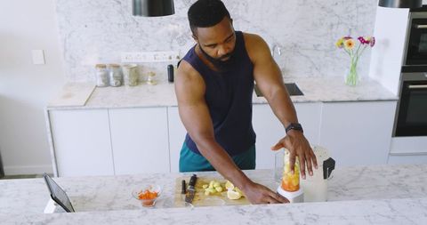 Athletic Man Preparing Fresh Smoothie in Modern Home Kitchen