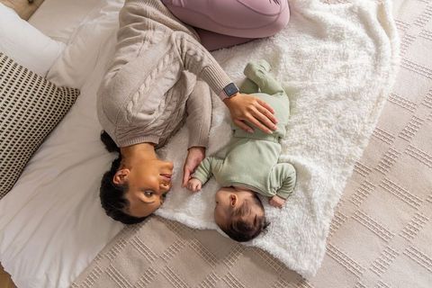 Mother bonding with newborn on plush blanket in cozy neutral bedroom for family lifestyle