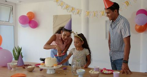 Family Celebrating Birthday, Sharing Cake and Wearing Party Hats