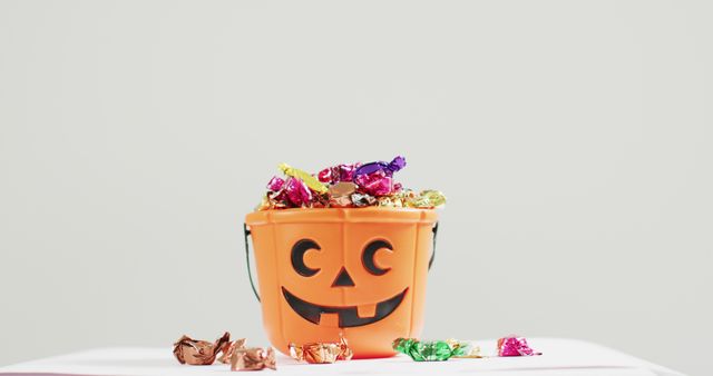 Halloween candy collection in a festive pumpkin bucket ideal for Halloween-themed designs. Perfect for promotional materials, party invitations, advertisements, and children's events.