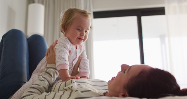 Caucasian mother smiling while playing with her baby on the bed at home. motherhood, love and childcare concept