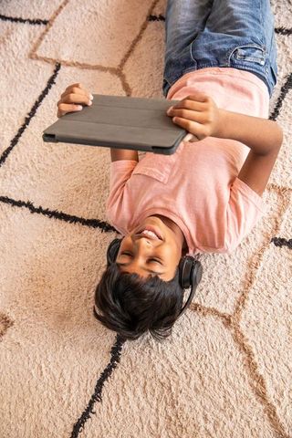 Smiling child relaxing at home with tablet and headphones