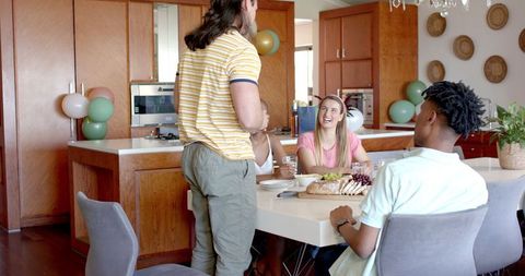 Friends Gathering Around Table Enjoying Meal Together in Cozy Kitchen