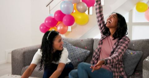 Two Women Celebrating at Home with Balloons and Confetti
