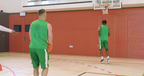 Coach directing diverse basketball teammates dribbling around cones and shooting on indoor court