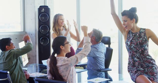 A mixed team of professionals joyously celebrates a success in their office. - Download Free Stock Photos Pikwizard.com