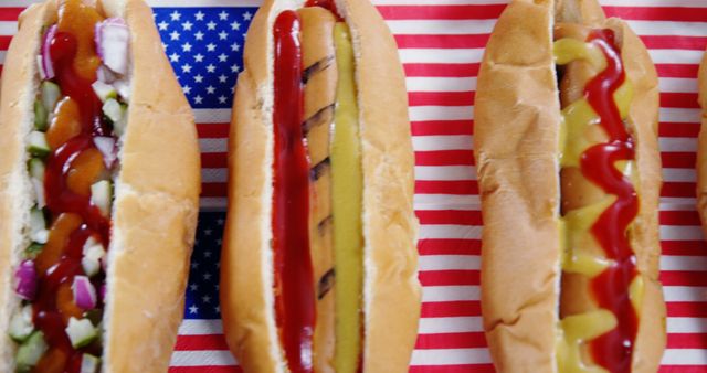Three grilled hot dogs with different toppings placed on a surface with an American flag background. Suitable for use in advertisements, food blogs, menus for American-themed restaurants, holiday celebrations, and culinary websites.