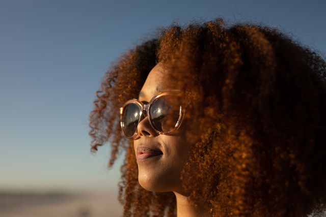 African American woman on a beach, wearing glasses, looking. Free time and vacation. 