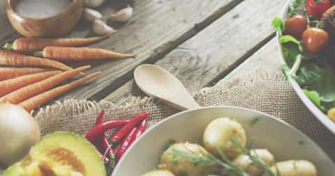 Serving boiled baby potatoes with herbs and fresh vegetables on rustic wooden table