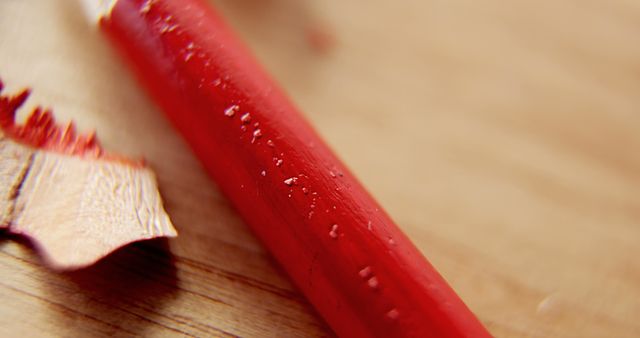 A close-up view of a sharpened red pencil and shavings on a wooden surface, with copy space. The focus on the pencil tip suggests precision, perhaps in an artistic or educational context.