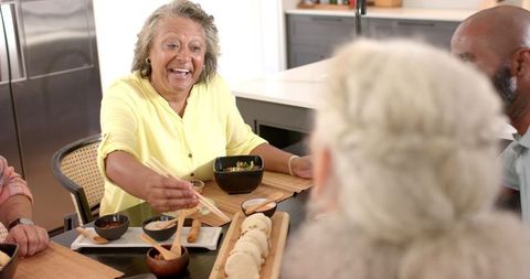 Senior Friends Laughing and Dining Together in Modern Kitchen
