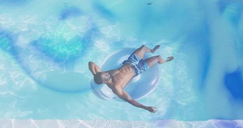 Relaxing on Clear Inflatable Ring in Private Pool Under Sunlit Blue Water and Ripples