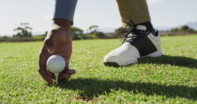 Image of hands and legs of african american man playing golf on golf field. sporty, active lifestyle and playing golf concept.