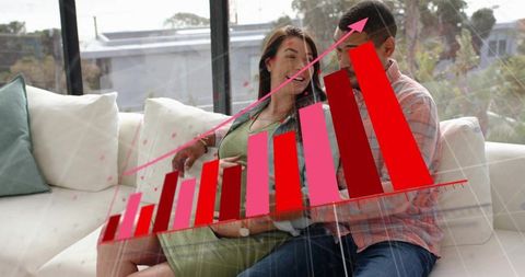 Pregnant partner relaxing on sofa with partner viewing tablet showing 3d growth chart