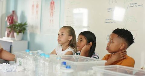 Elementary students observing hands-on science demonstration with recycled bottles