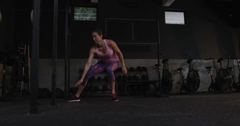 Dynamic athletic woman training in dark gym environment