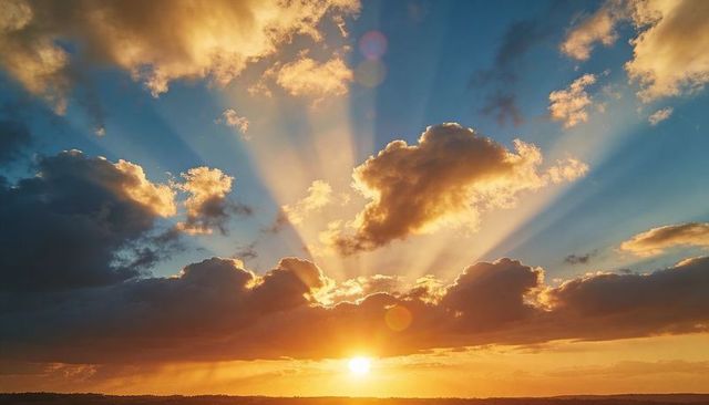 Golden Crepuscular Rays Breaking Through Cumulus Clouds Over Coastal Horizon at Sunrise
