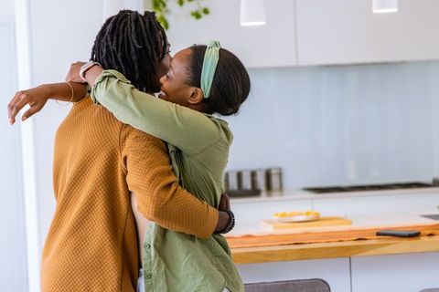African american couple embracing in bright modern kitchen showing affection and joy