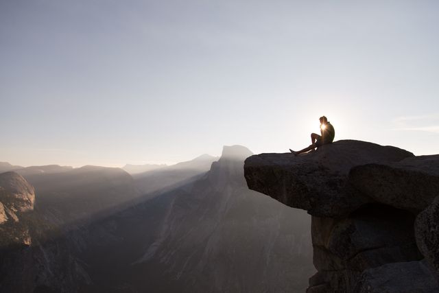Person Sitting on Cliff Edge Overlooking Mountain Valley at Sunrise - Download Free Stock Photos Pikwizard.com