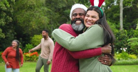 Diverse family hugging outdoors in festive knitwear