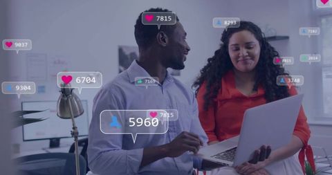 Colleagues reviewing social media engagement metrics on laptop in modern office