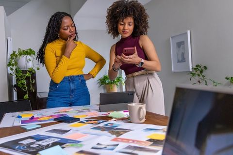 African american women collaborating on moodboard and branding concepts in studio workspace