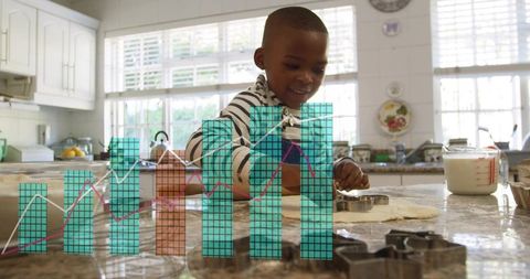 Smiling boy baking and cutting dough on sunlit granite countertop with data chart overlay