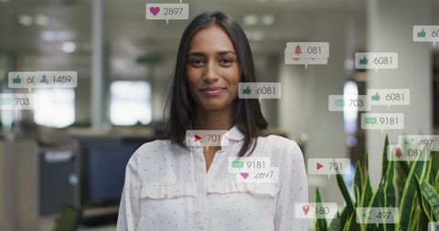 Smiling woman in office with social media notifications